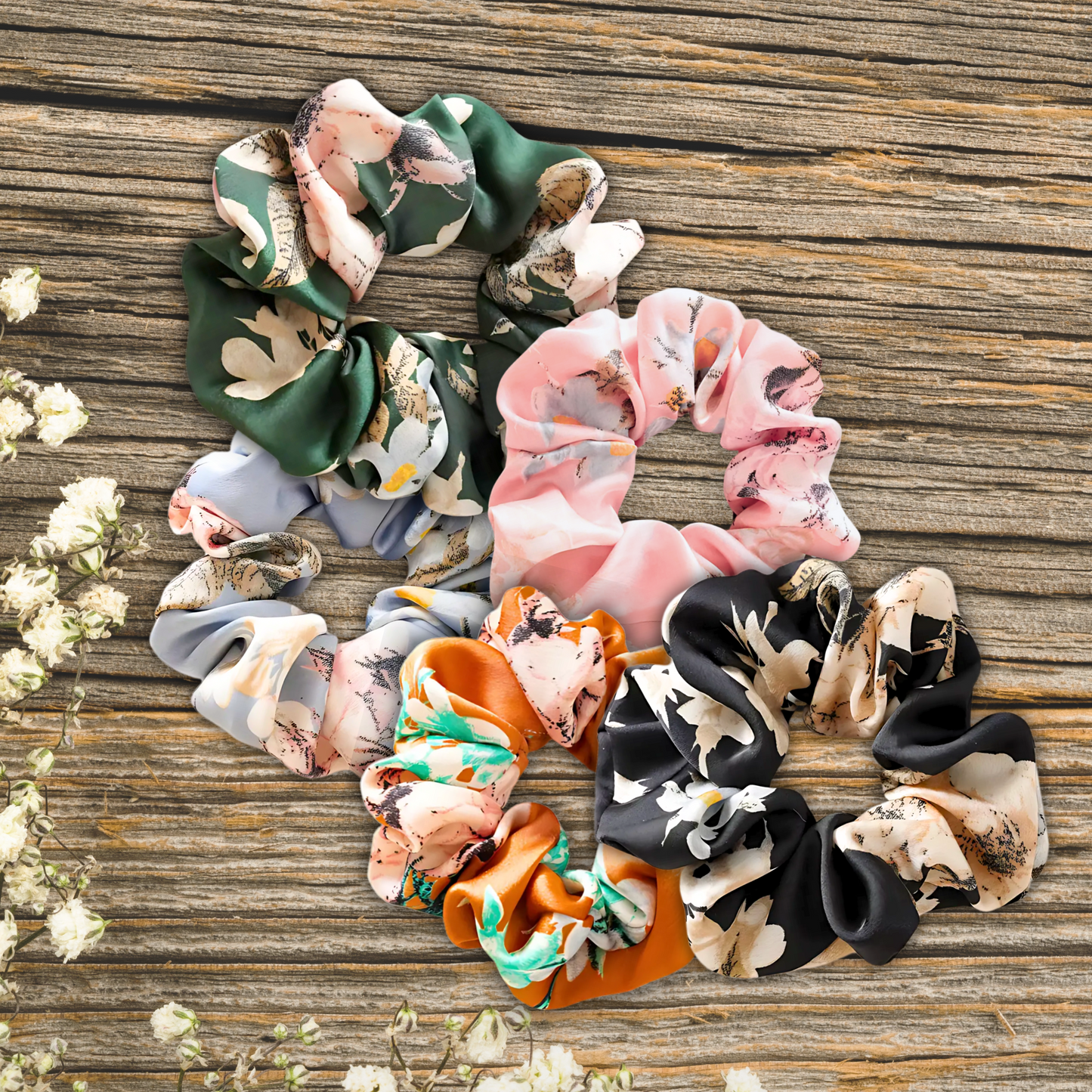 floral satin scrunchies on a wooden plank background in the colors, Evergreen Petals, Peach Blossom, Sky Blossom, Amber Bloom, and Midnight Bloom.