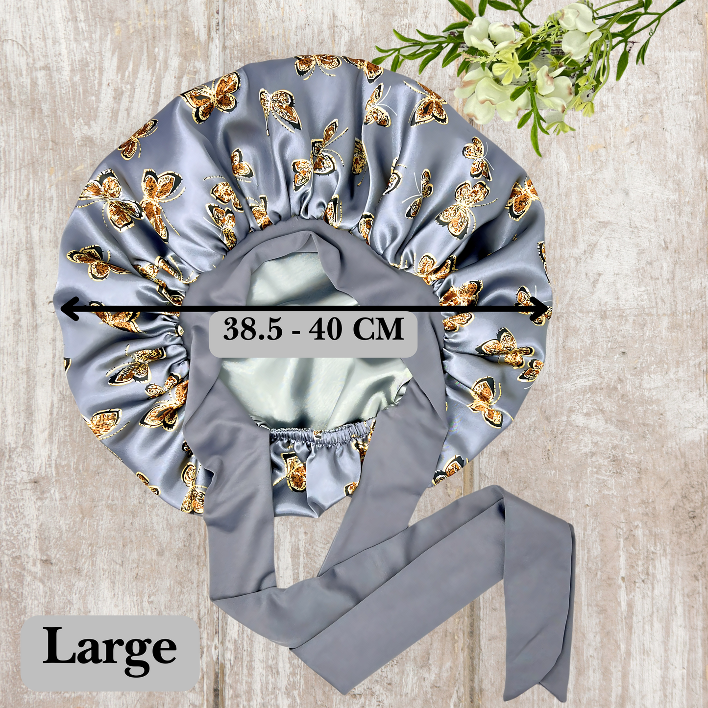 Beautiful stretch tie gray butterfly printed satin lined satin hair bonnet on a light wood background