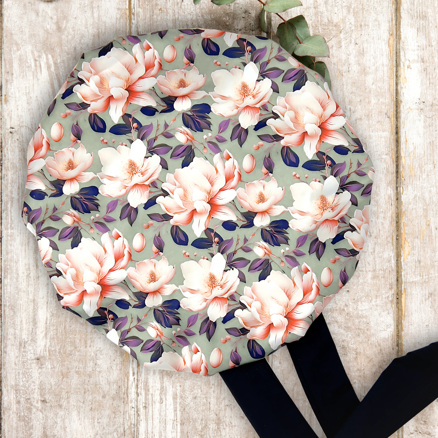 Elegant olive colored satin bonnet with a floral print, featuring a black stretch tie band for a secure and stylish fit, displayed on a wooden background.