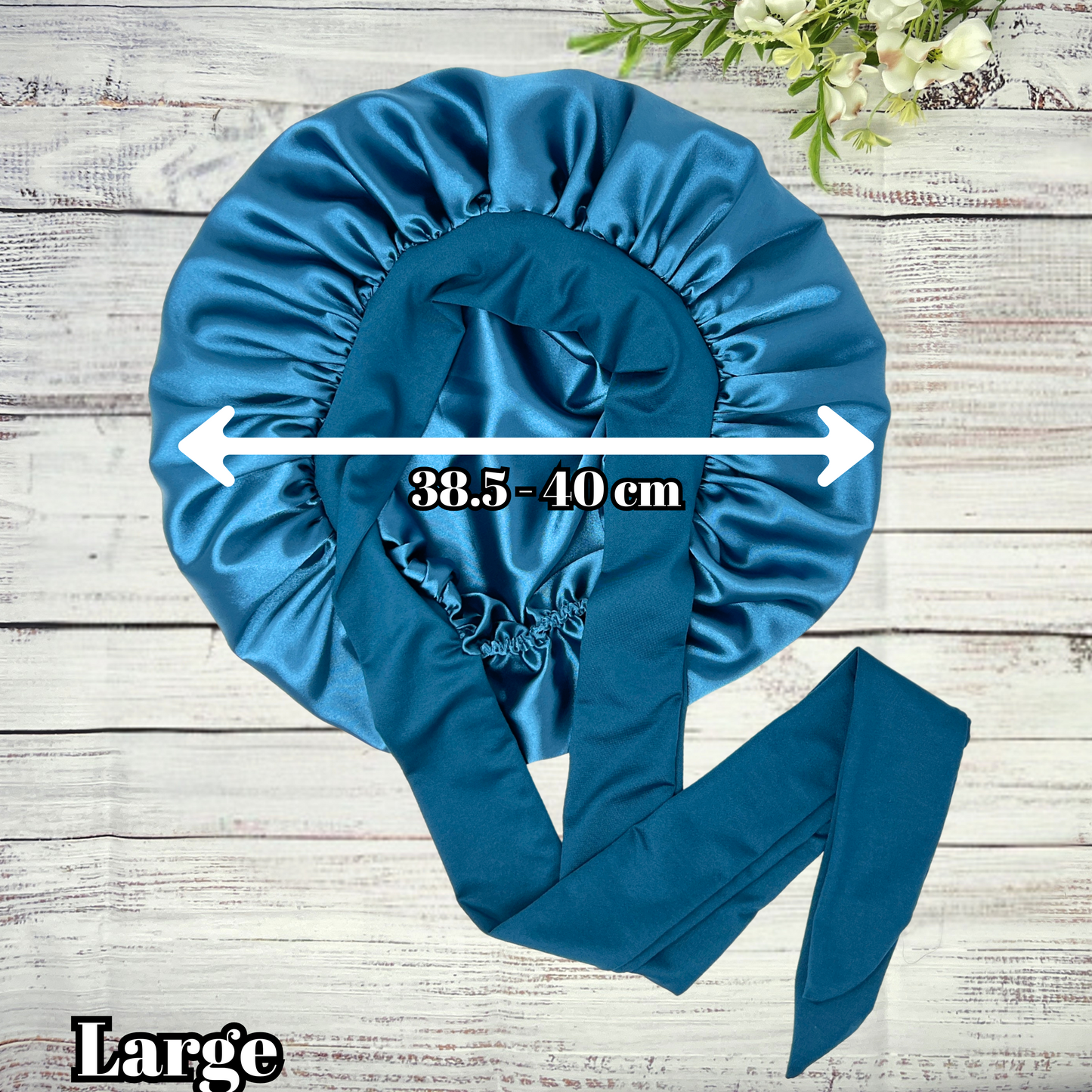 Large Peacock blue satin hair bonnet displayed on a light wood background, showcasing smooth satin texture and vibrant color. Ideal for curly, natural, and protective hairstyles.