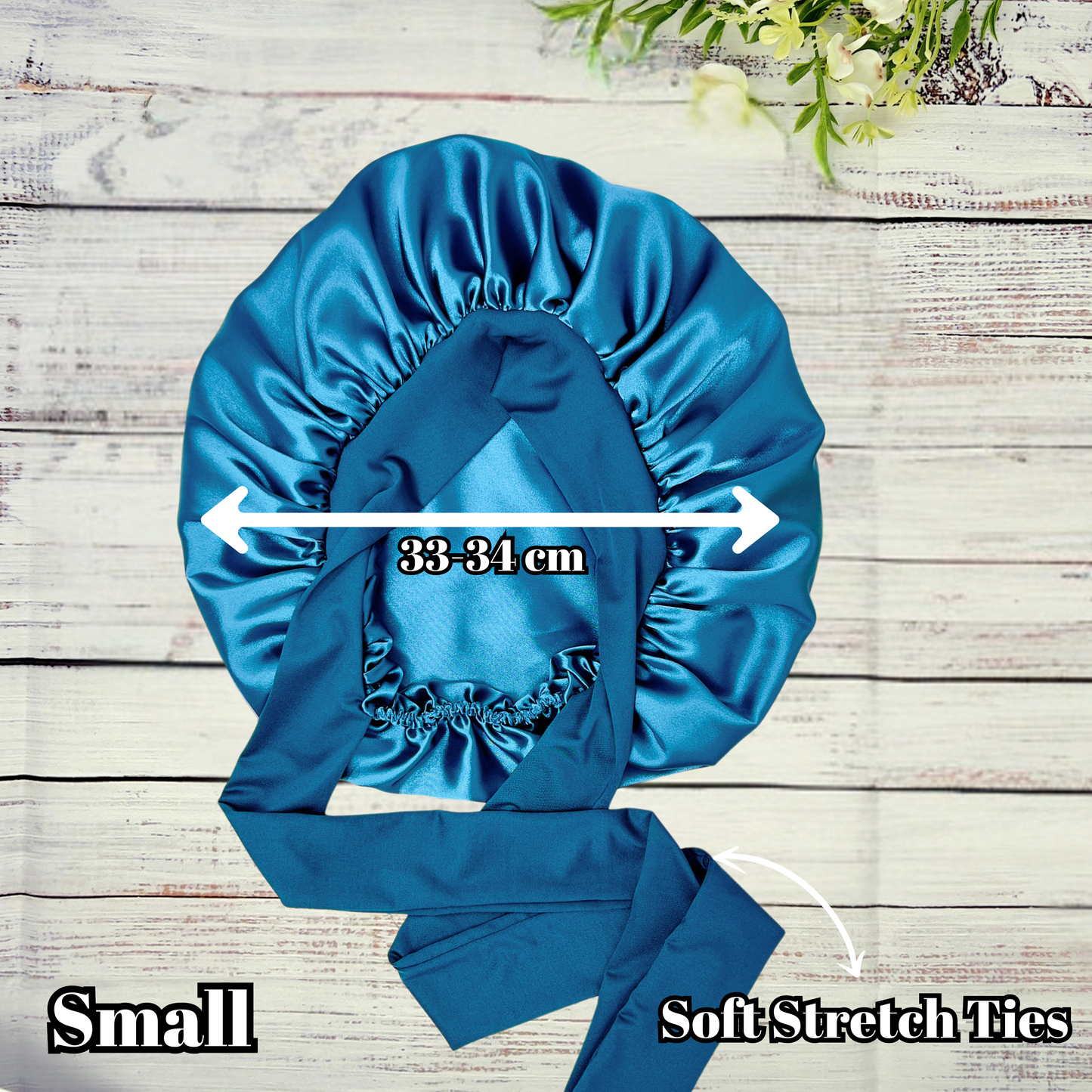 Peacock blue satin hair bonnet displayed on a light wood background, showcasing smooth satin texture and vibrant color. Ideal for curly, natural, and protective hairstyles.