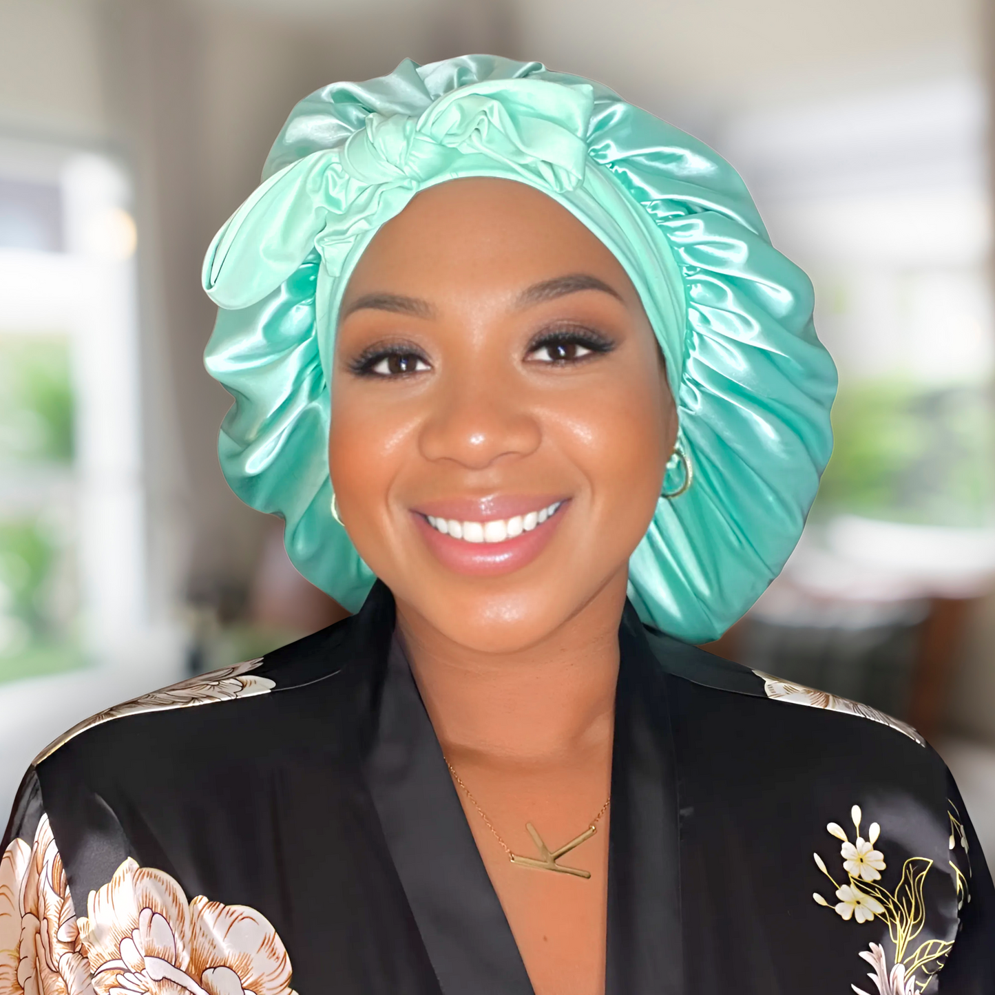 African American woman wearing an Aqua Green bonnet in a blurred living room background.
