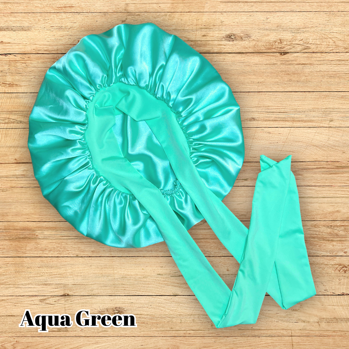 Aqua green stretch tie bonnet on wooden table.
