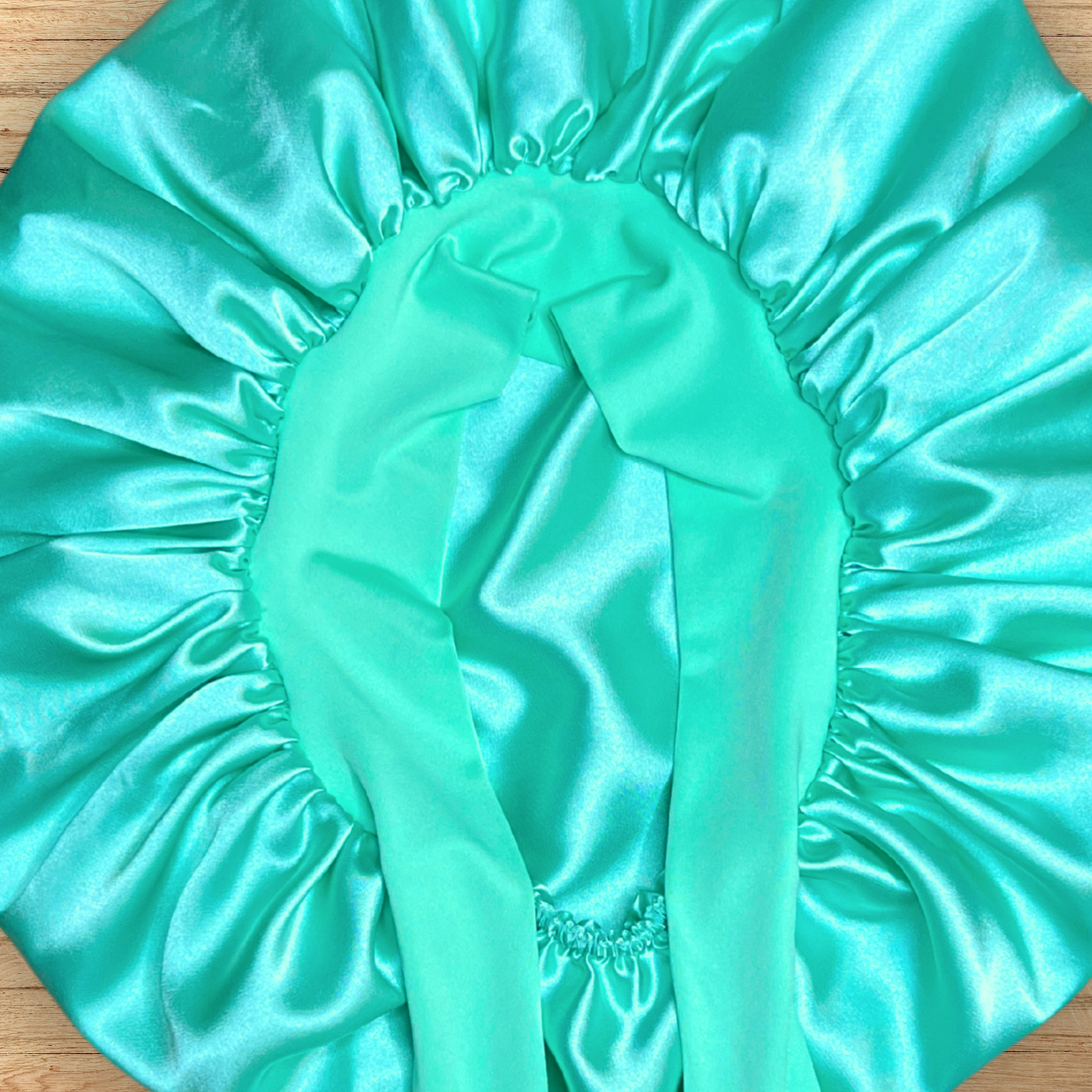 close up view of Aqua green stretch tie bonnet on wooden table.