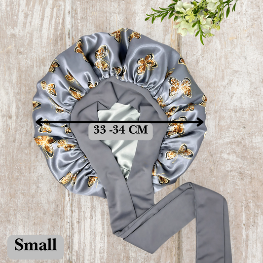 Beautiful stretch tie gray butterfly printed satin lined satin hair bonnet on a light wood background
