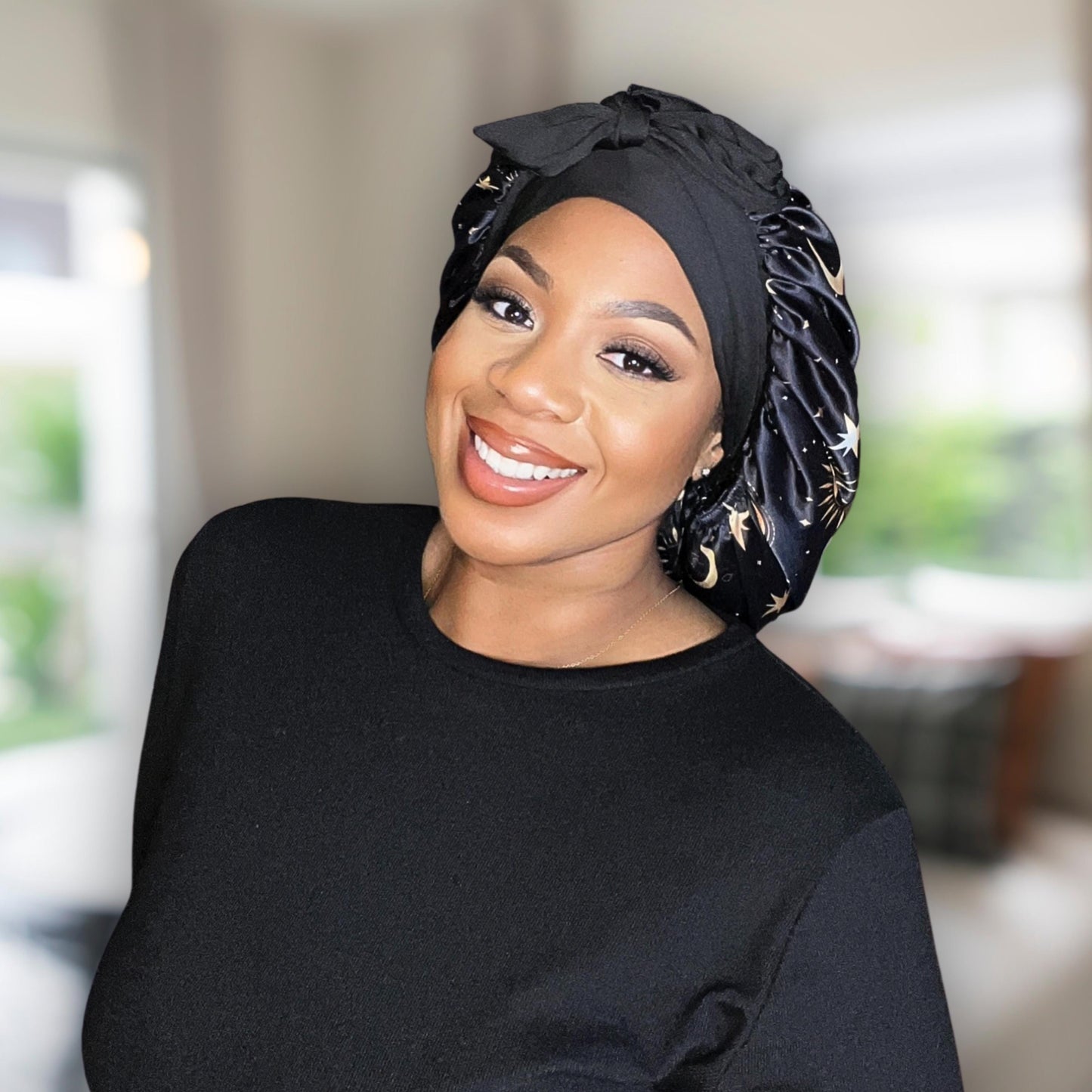 African American model wearing a handmade Charmeuse Silk Satin Sleep Bonnet in a Celestial Starry Night Cosmic Print with adjustable stretch ties. Features a double-layer satin design that protects hair from frizz and breakage while locking in moisture. Unisex silk bonnet made in the USA by Prince Hair Company.