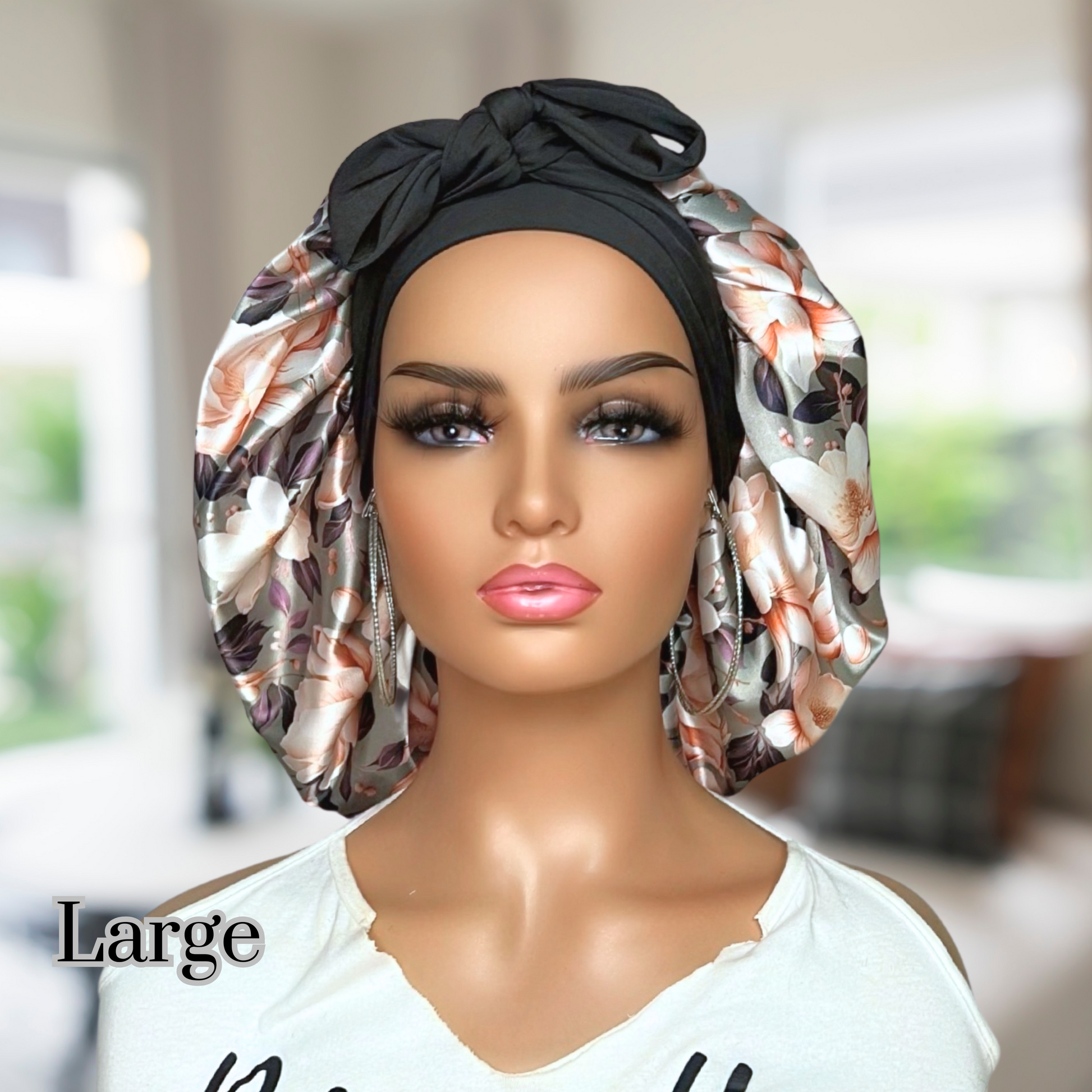 Elegant olive colored satin bonnet with a floral print, featuring a black stretch tie band for a secure and stylish fit, displayed on a wooden background.