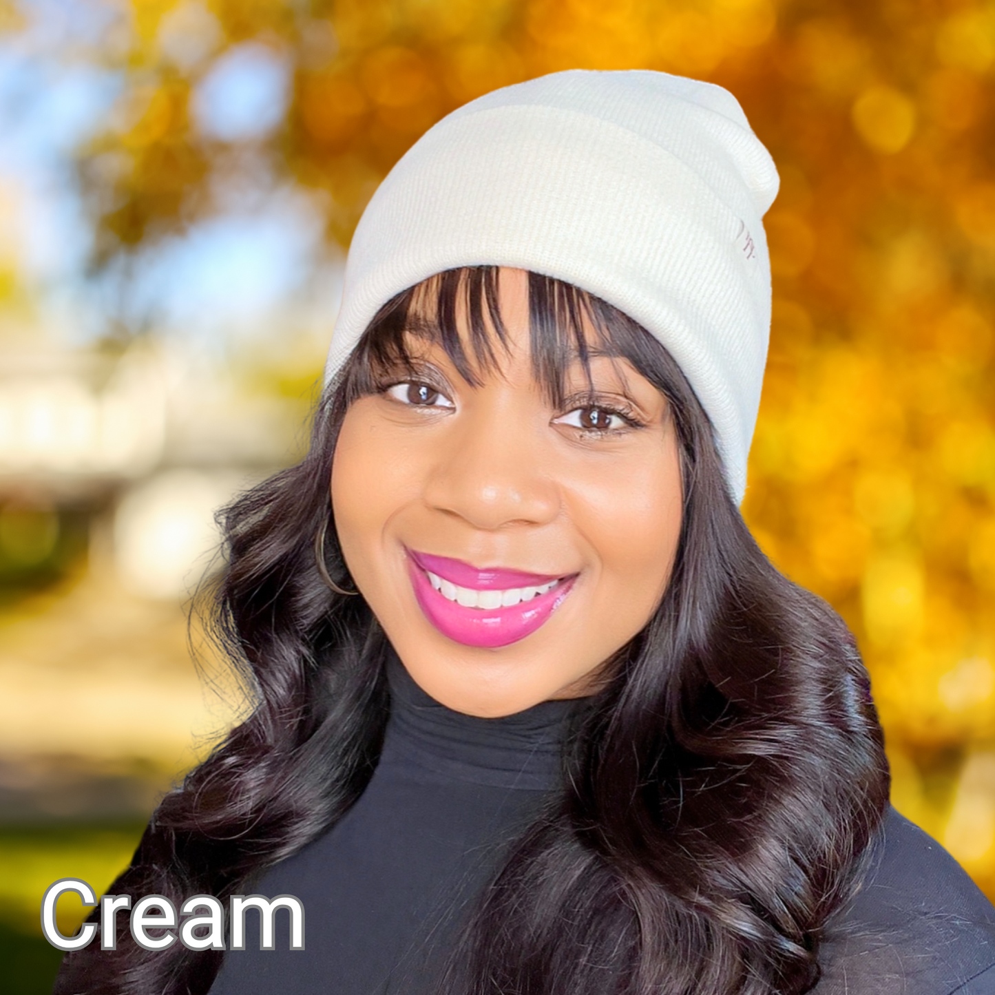 African American female modeling a cream colored satin lined beanie on a fall blurred background.