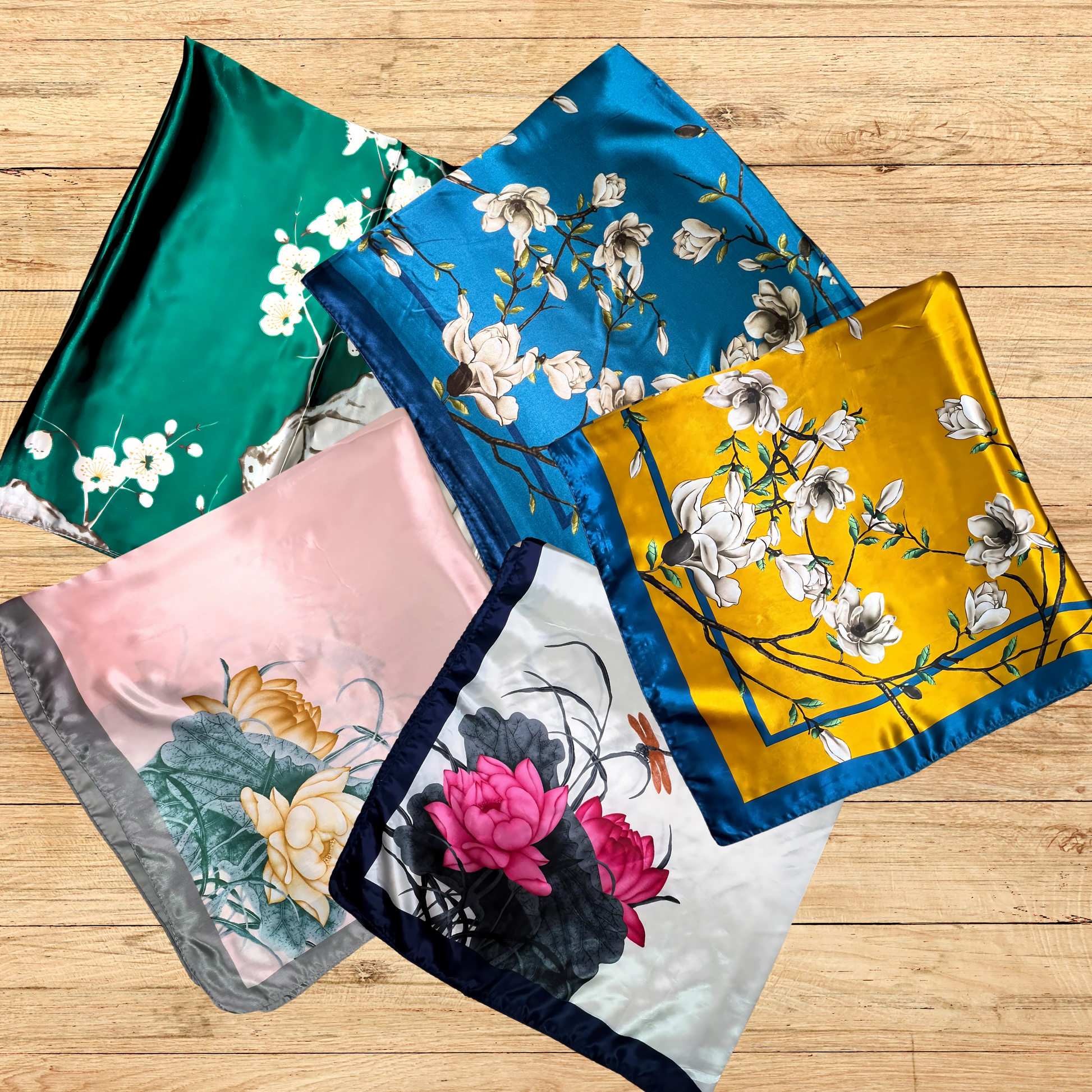 square  satin floral hair scarves on a wooden table showcasing the different patterns being offered.