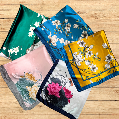 square  satin floral hair scarves on a wooden table showcasing the different patterns being offered.