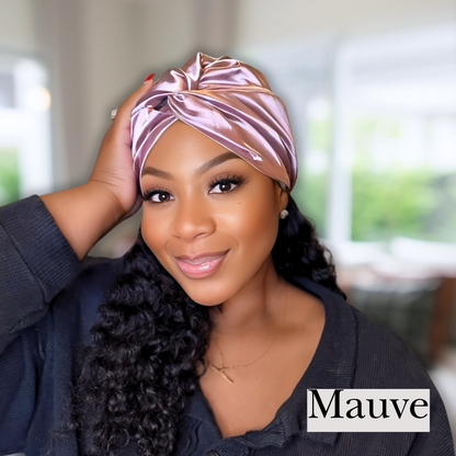 beautiful model in blurred living room wearing a mauve colored all satin hair turban. Perfect for chemo caps, hair bonnets and silky sleep caps. 