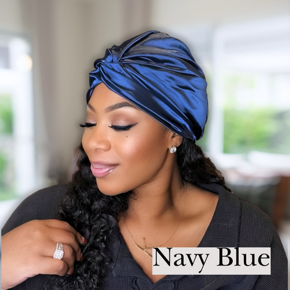 beautiful model in blurred living room wearing a navy blue colored all satin hair turban. Perfect for chemo caps, hair bonnets and silky sleep caps. 