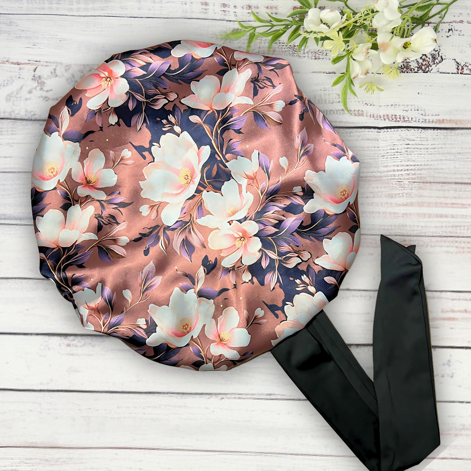 Beautiful brown magnolia flower bonnet with a silky satin gold lining with long black stretch ties on a wooden background. 