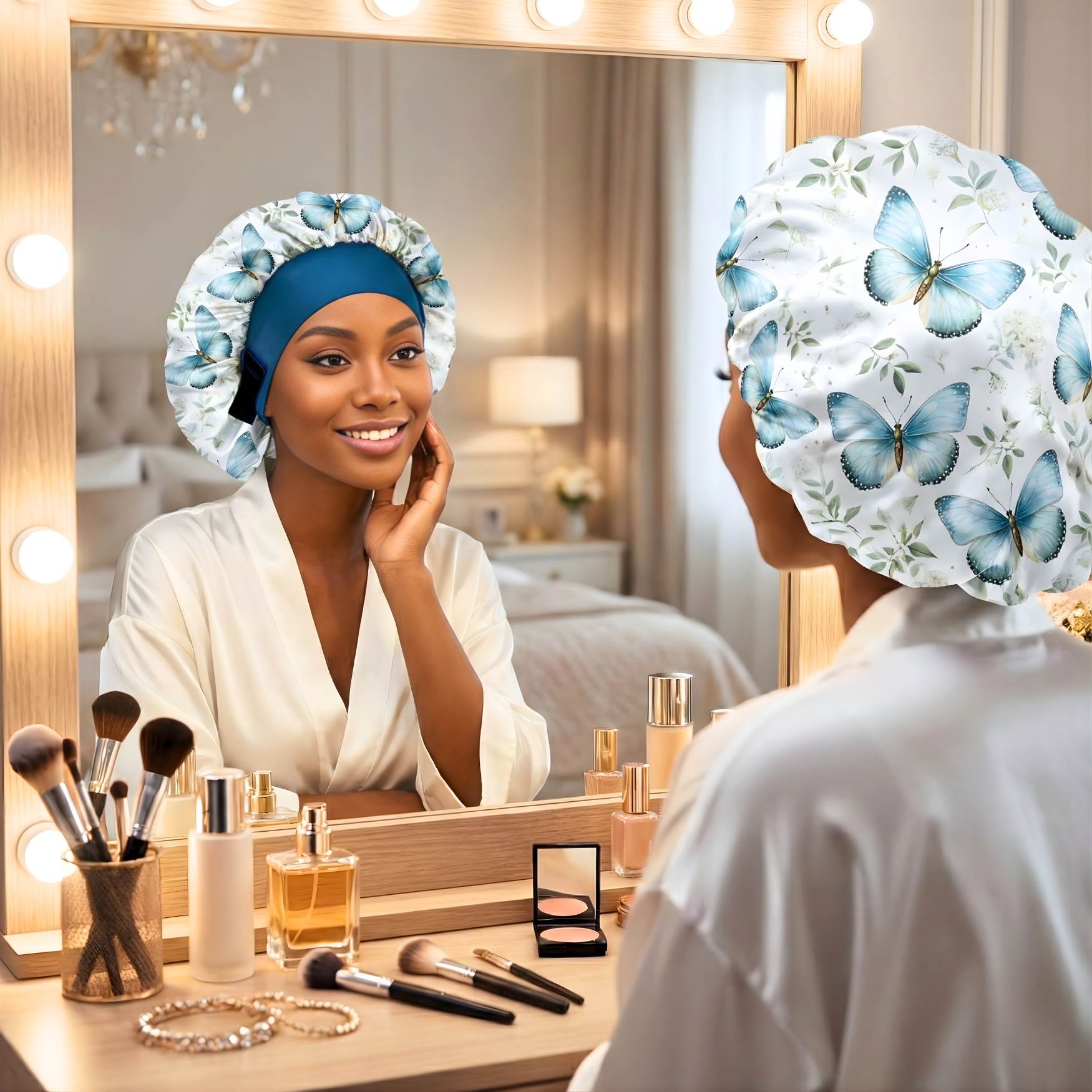 Woman in a cozy bedroom wearing a Charmeuse silk satin no-slip wide band hair bonnet in a floral butterfly print with powder blue lining and a deep peacock blue band, looking at herself in the mirror while protecting her natural hair overnight.