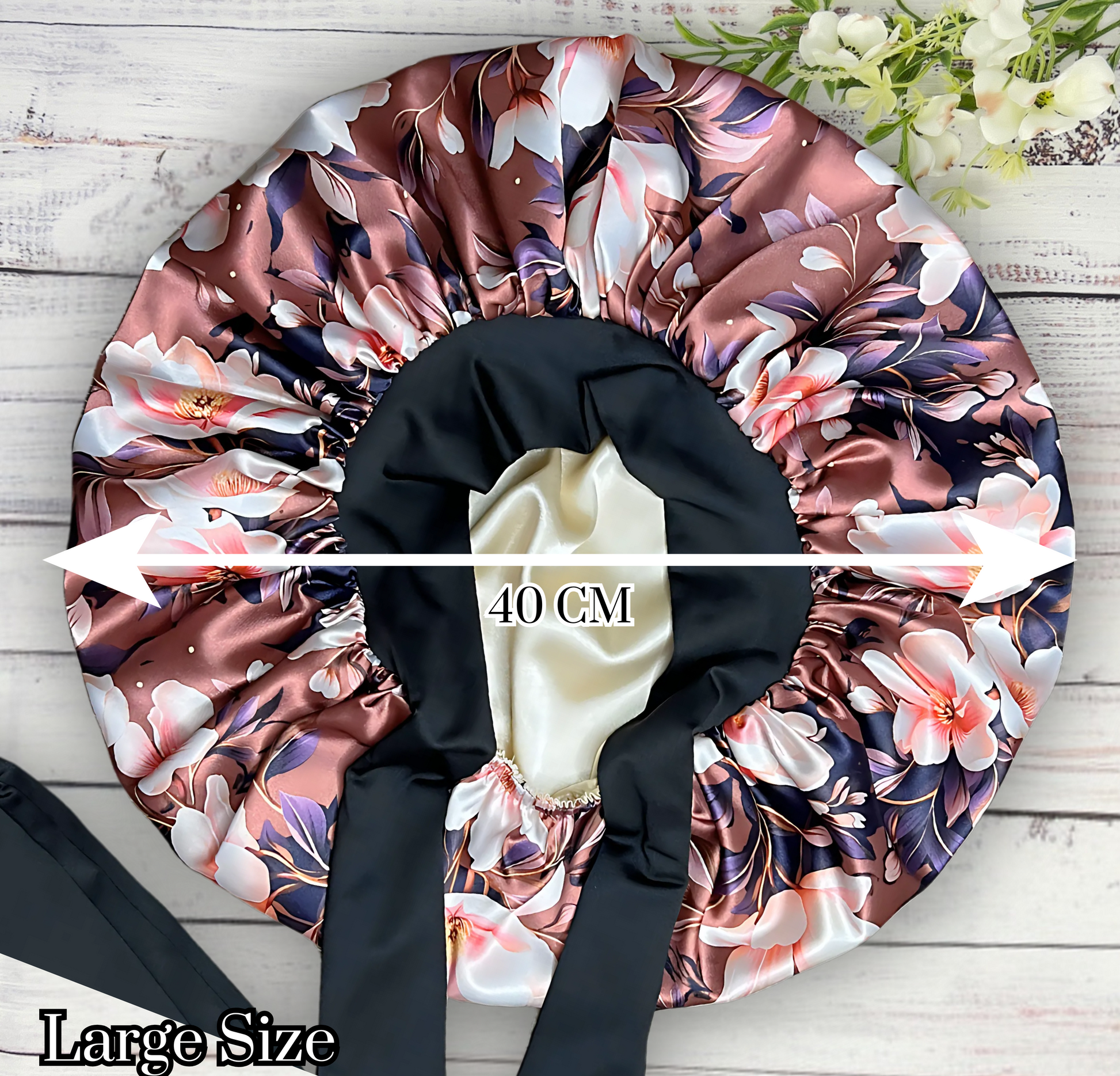 Beautiful brown magnolia flower bonnet with a silky satin gold lining with long black stretch ties on a wooden background. 