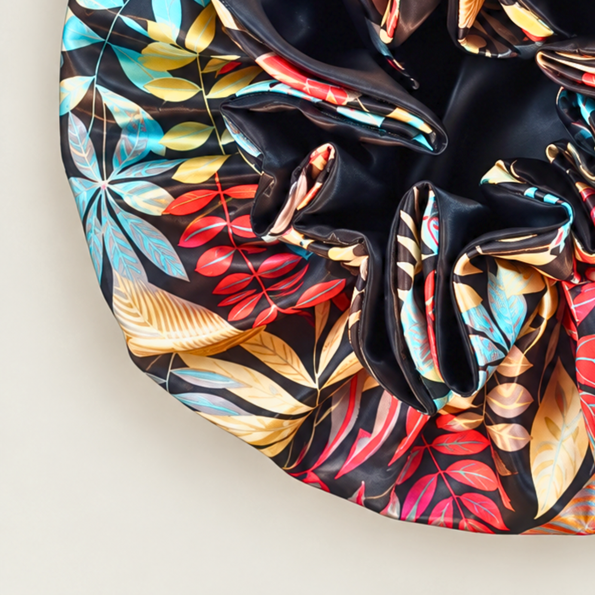 Close-up of the Black Autumn ruffle satin bonnet, black with red, yellow and blue leaf print