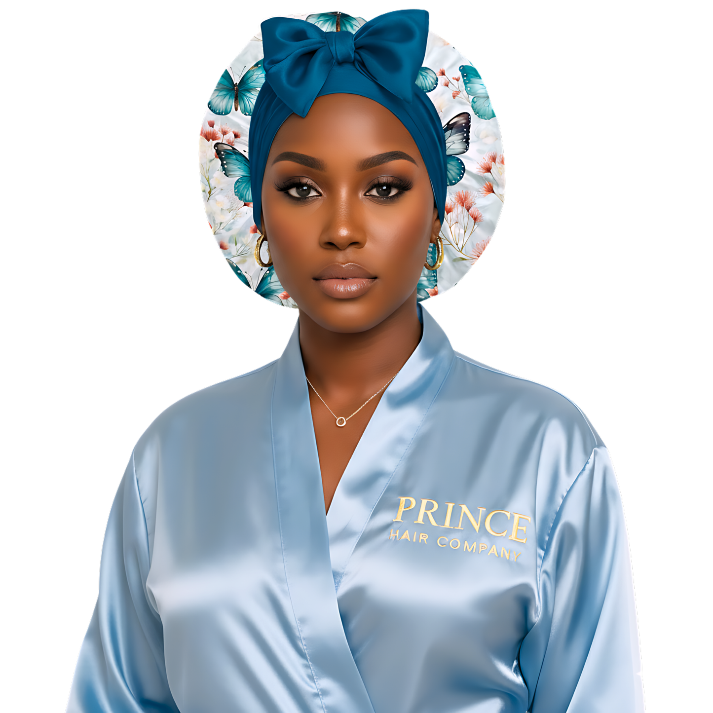 A woman wearing a light blue satin robe with “Prince Hair Company” in gold lettering poses confidently against a white background. She wears a blue butterfly-print charmeuse satin bonnet with a matching blue stretch tie and bow, showcasing a polished and elegant look that highlights the bonnet’s luxurious design and fit.
