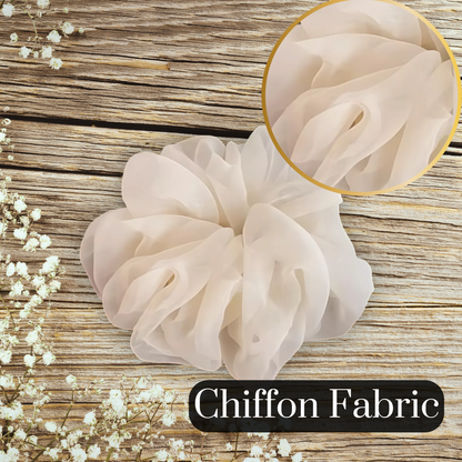 close up view of a chiffon scrunchie in beige on a large wood table measuring 16 cm in diameter