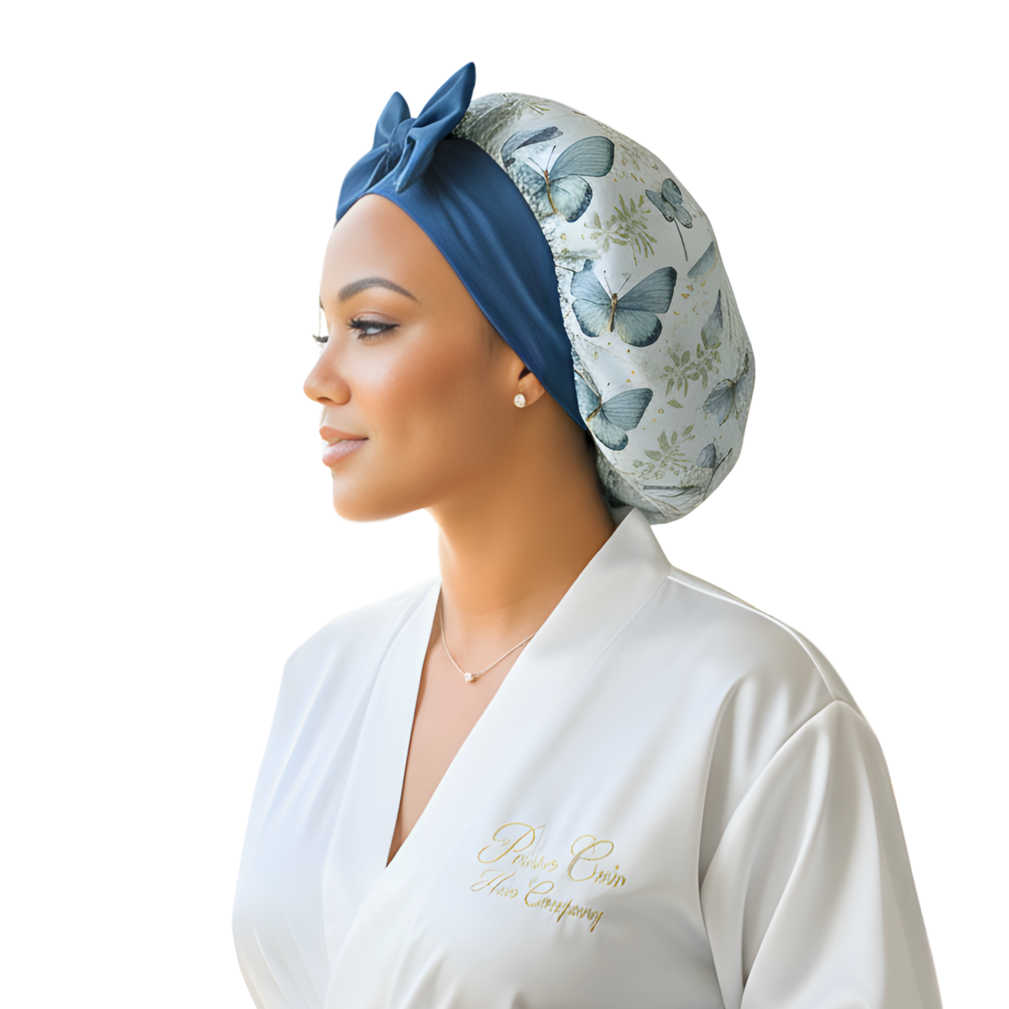 Side profile of a woman wearing a white robe and a handmade charmeuse silk hair bonnet with a floral butterfly print, gazing thoughtfully into the distance. The small satin bonnet fits comfortably on short to mid-back length hair—straight, curly, wavy, natural, braided, or thick—and helps protect against frizz, dryness, and breakage. A luxury handmade sleep cap designed by Prince Hair Company in Chicago.