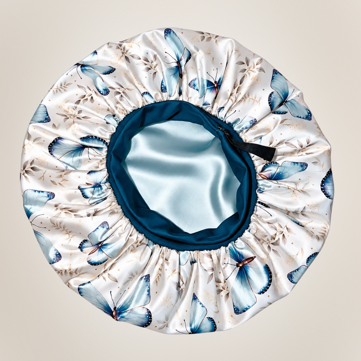 Inside view of the Floral Butterfly bonnet, showing blue butterflies on white fabric, a blue band, pale blue lining and black elastic strap.