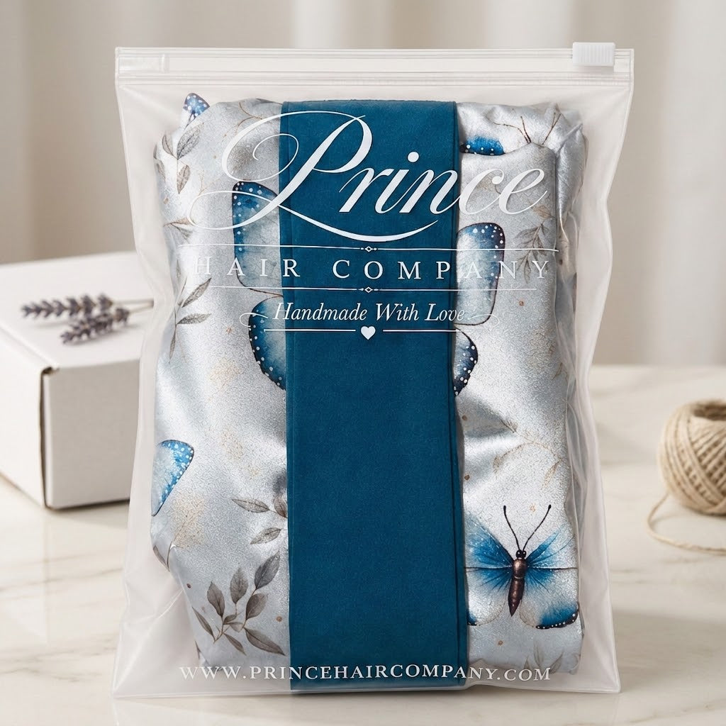 A packaged hair extension or hair fabric piece from Prince Hair Company, sealed in a clear plastic bag with a white branded label and a dark blue vertical band. The product inside has a silver-gray base with blue butterfly motifs and gray leaf patterns.
