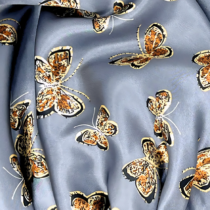 Close view of a beautiful stretch tie gray butterfly printed satin lined satin hair bonnet on a light wood background 
