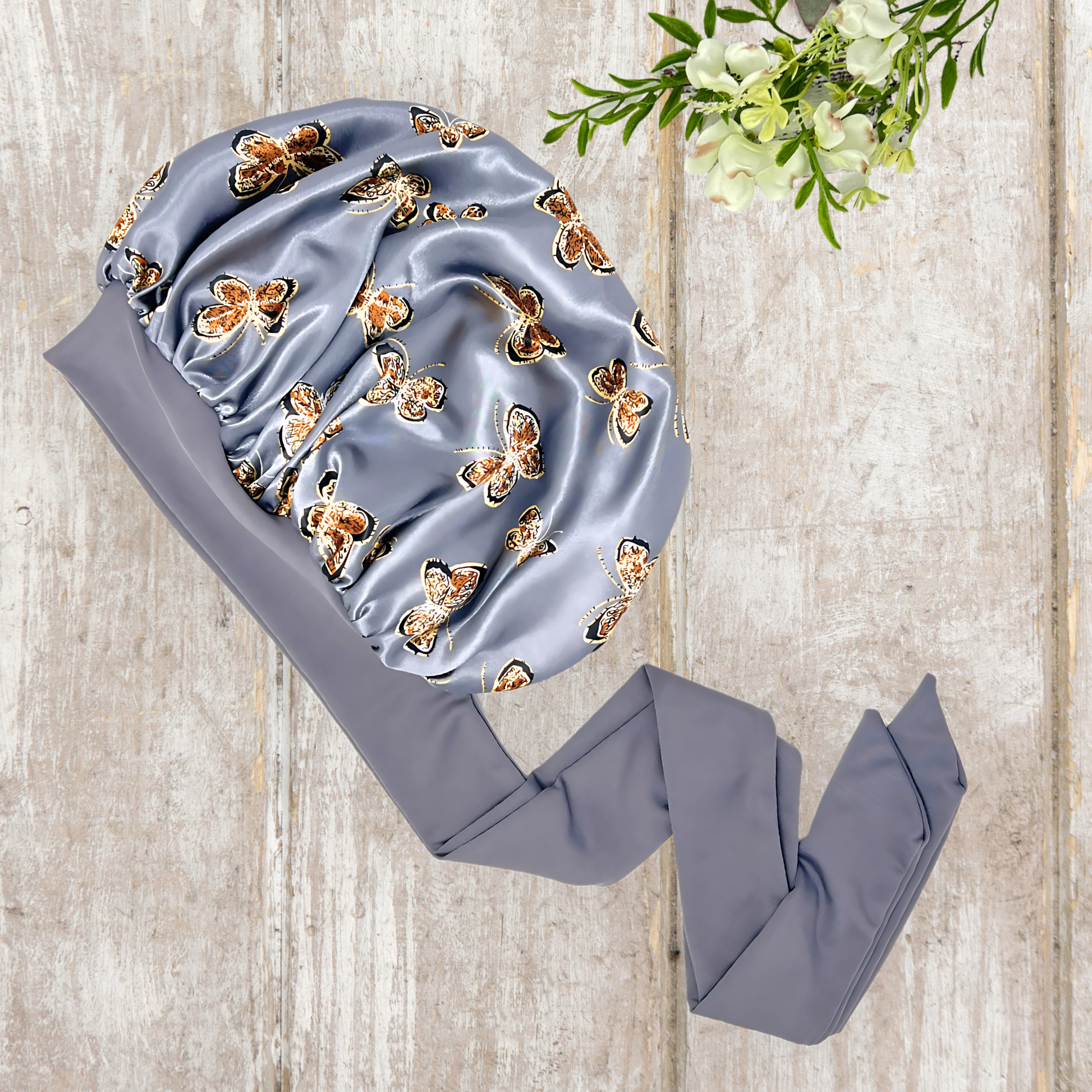 Beautiful stretch tie gray butterfly printed satin lined satin hair bonnet on a light wood background 