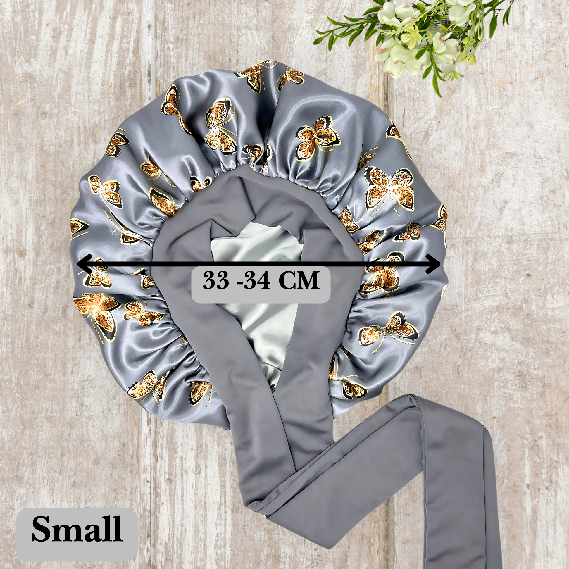 Beautiful stretch tie gray butterfly printed satin lined satin hair bonnet on a light wood background 
