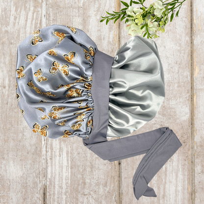 Beautiful stretch tie gray butterfly printed satin lined satin hair bonnet on a light wood background 