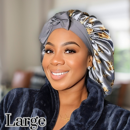 Beautiful woman modeling a large stretch tie gray butterfly printed satin lined satin hair bonnet in a blurred living room. 