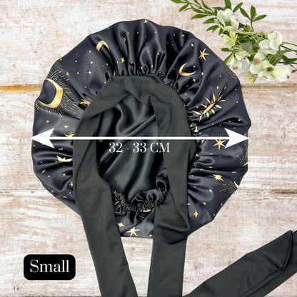 32-33 cm Small size handmade Charmeuse Silk Satin Sleep Bonnet in a Celestial Starry Night Cosmic Print with adjustable stretch ties. Features a double-layer satin design that protects hair from frizz and breakage while locking in moisture. Unisex silk bonnet made in the USA by Prince Hair Company.