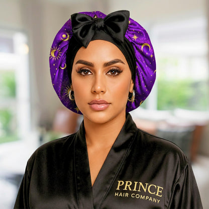 Close-up portrait of a model wearing the purple and gold Celestial Plum satin bonnet showing the secure forehead fit and bow detail.