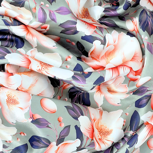 Close up beauty shot featuring smooth satin bonnet with peach and ivory magnolia print on sage background.