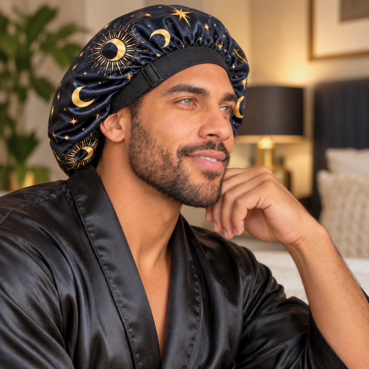 Side view of a man relaxing in a Starry Night satin bonnet and black robe, showing the adjustable wide band.