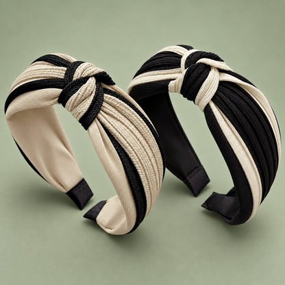 Two beige and black twisted knot headbands arranged side by side with striped fabric and padded ends visible.