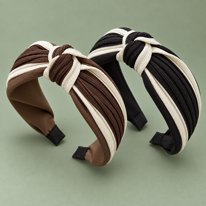 Brown and cream twisted knot headband beside black and cream twisted knot headband on a sage green background.