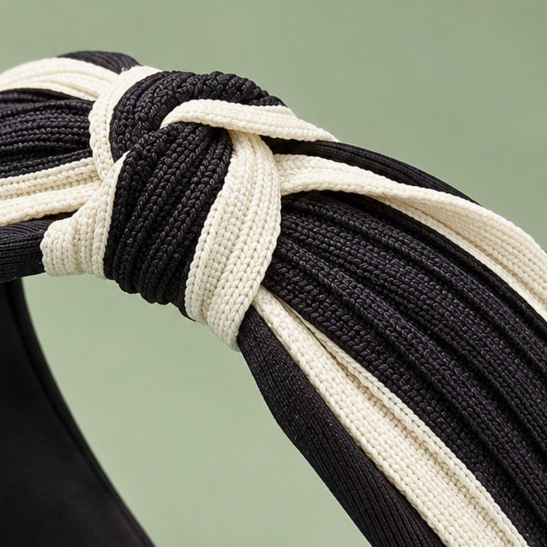 Close-up of the black and cream braided fabric and center knot on a two-tone twisted headband.