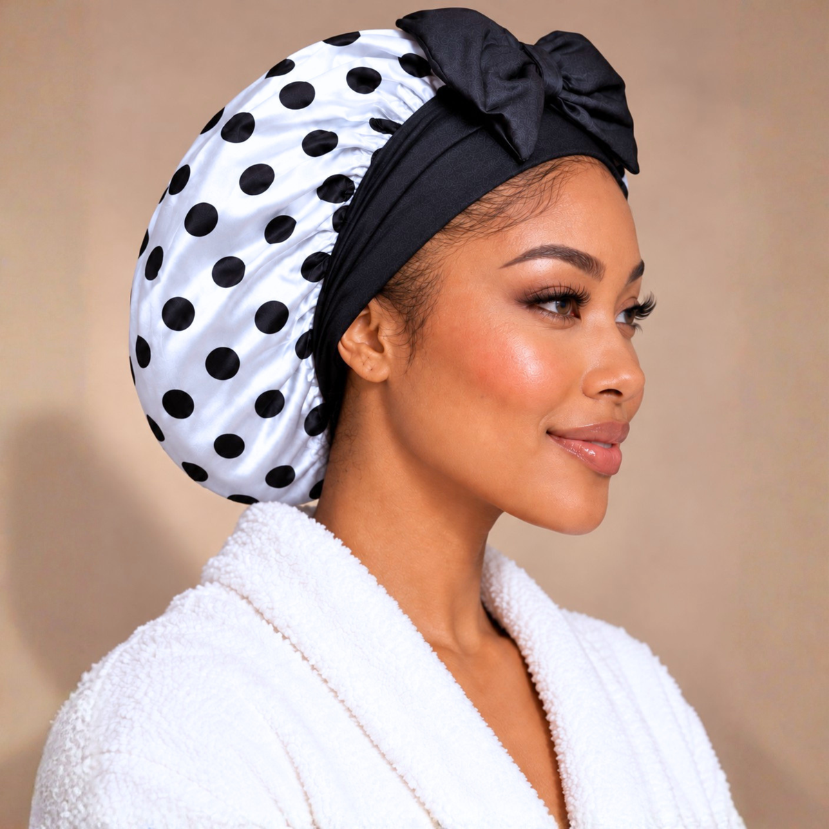 Side view of a white satin bonnet with black polka dots and black stretch-tie bow