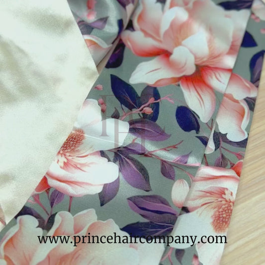 Video of a reversible olive magnolia floral print satin hair bonnet with champagne color interior on a wooden background.