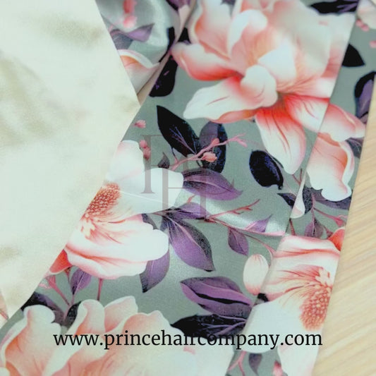 Video of a reversible olive magnolia floral print satin hair bonnet with champagne color interior on a wooden background.