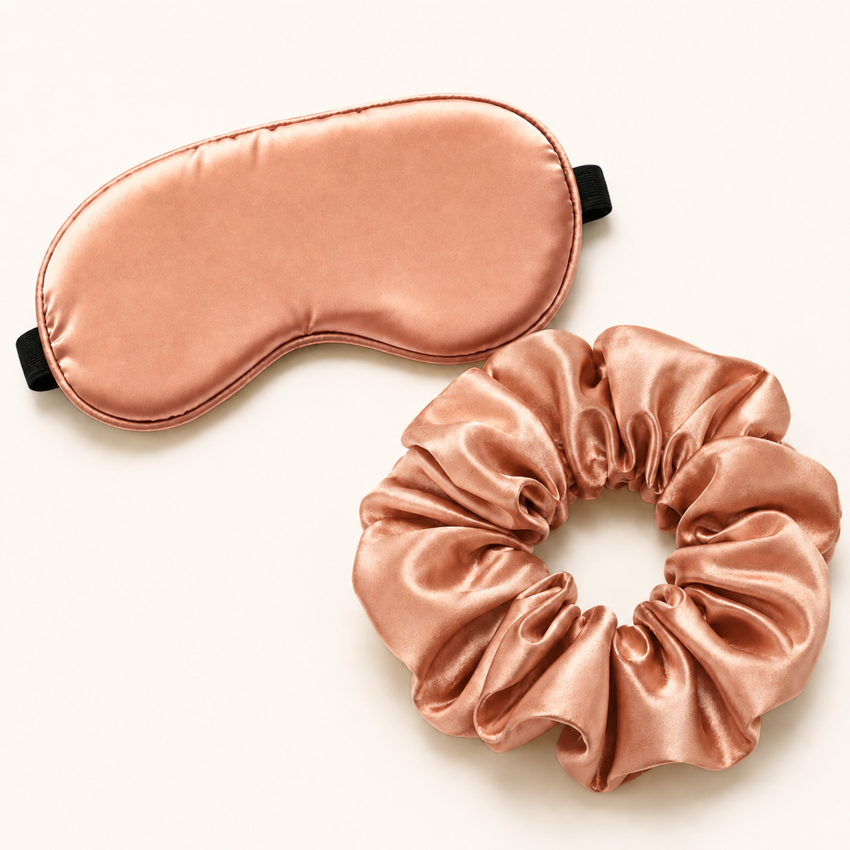 Rose gold satin sleep set with adjustable eye mask and oversized scrunchie on white background