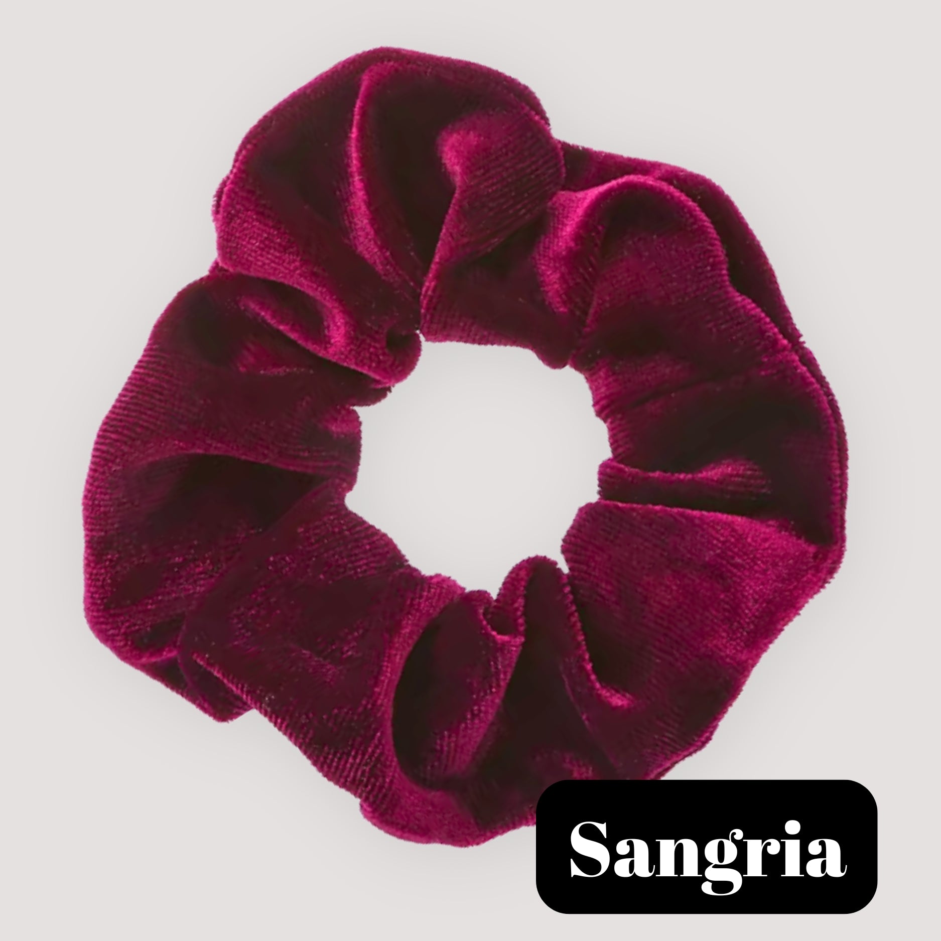 A single Sangria burgundy handmade velvet scrunchie for damage-free hair styling on a light background, featuring a black label reading 'Sangria