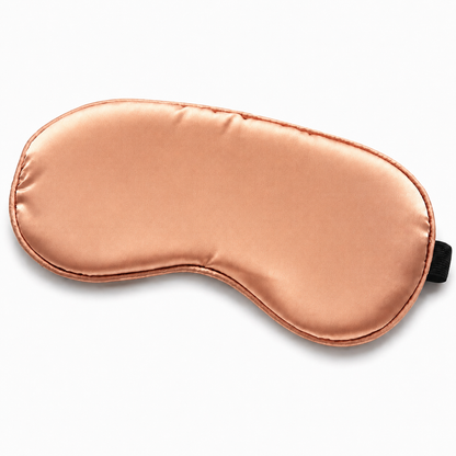 Rose gold satin sleep mask with adjustable black elastic strap on white background