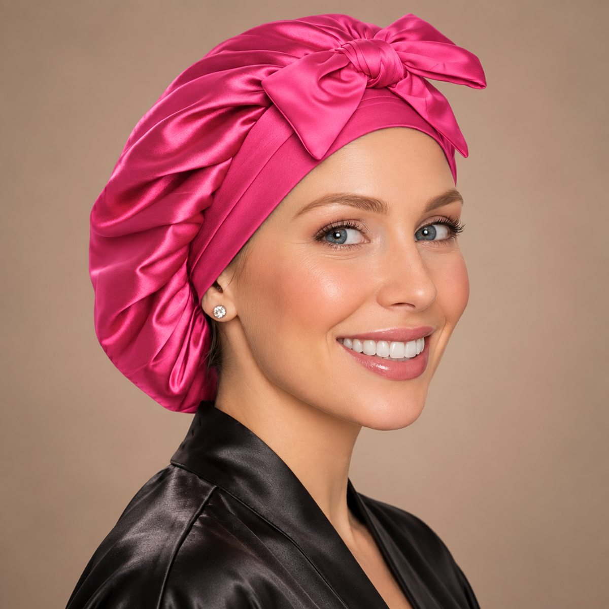 Small hot pink satin bonnet with matching bow, shown from a side angle
