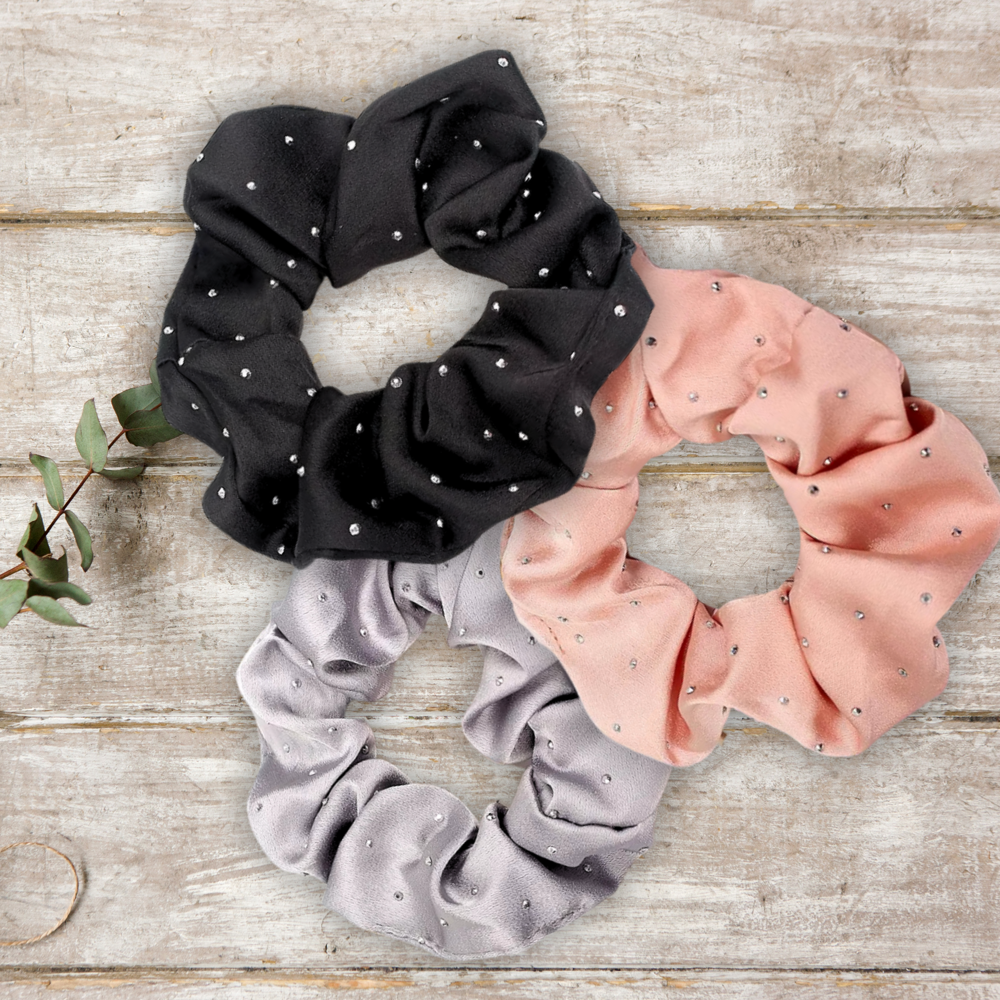 main image of black, rose gold and silver satin rhinestone scrunchies on a wood background