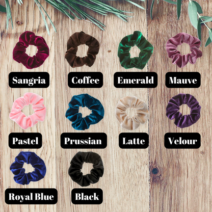 multiple velvet color scrunchies on a wooden background.