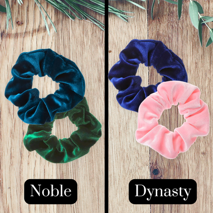 Prussian blue, emerald green, royal blue and pink velvet scrunchies on a wooden background.